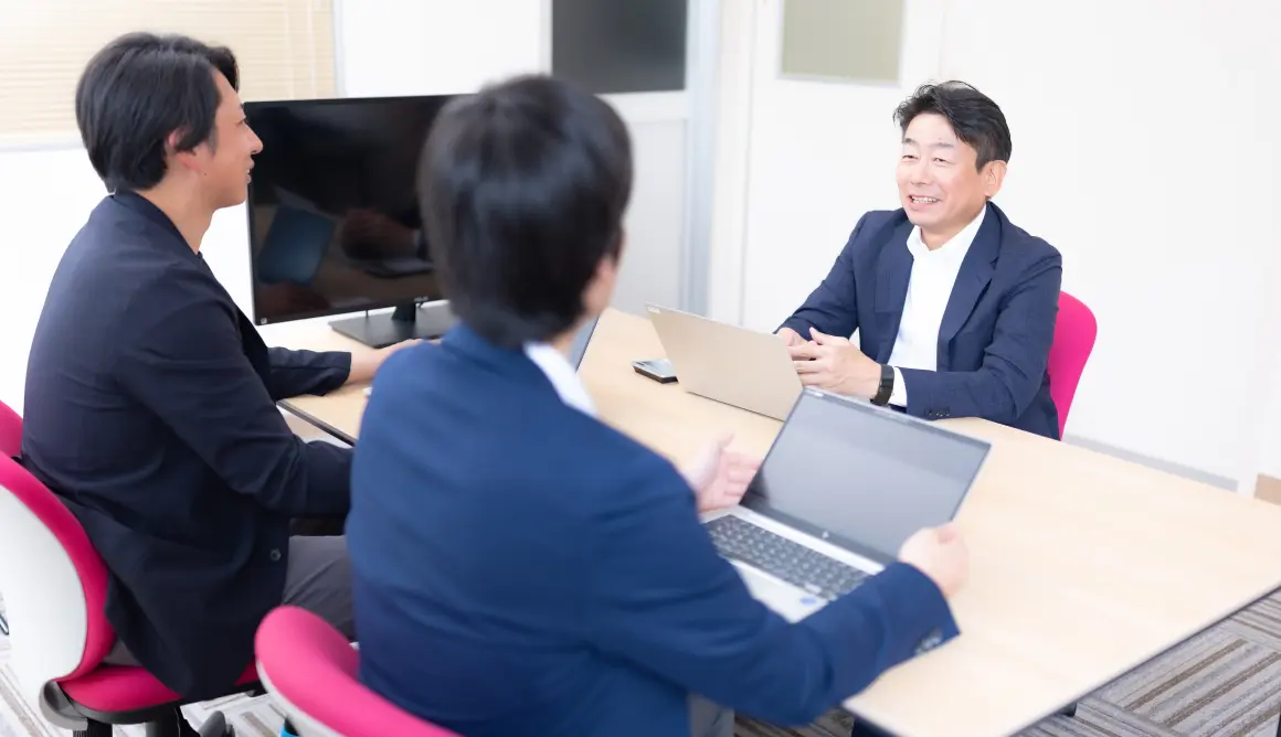 3人がパソコンを見ながら打ち合わせをしている様子の写真